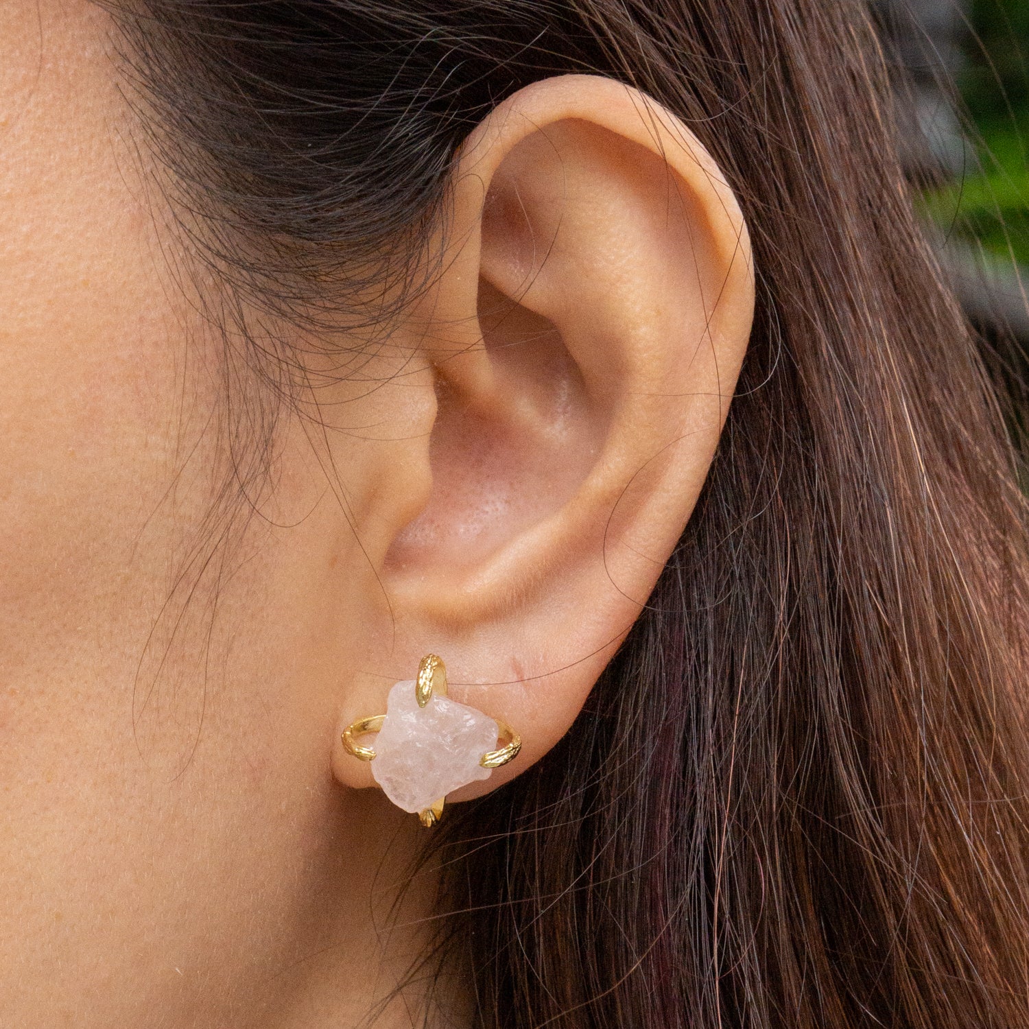 A close-up of a person's ear wearing a small gold stud earring with a pale pink stone. Elemental Rose Crystal Adjustable Earring by wjy studio