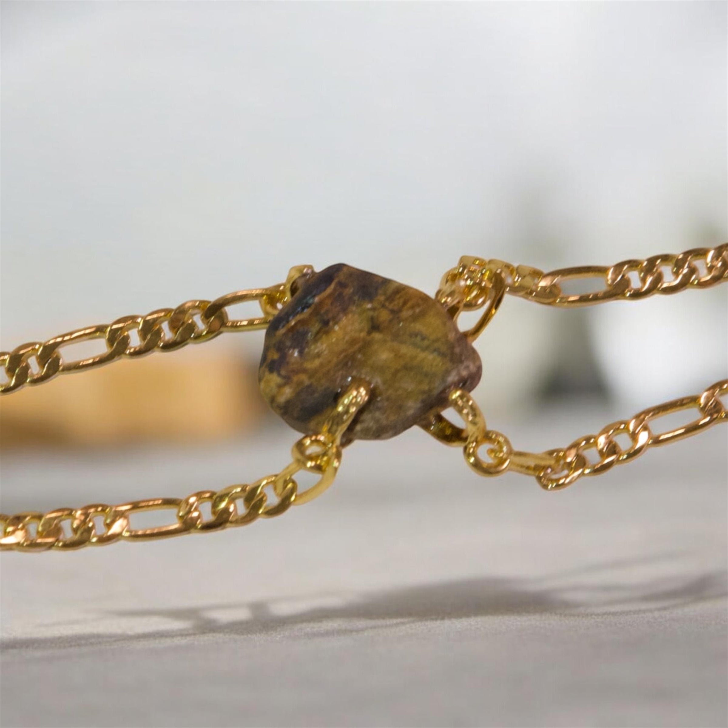 A close-up of a Elemental Rose Tiger’s Eye Bracelet  featuring a central, irregular natural brown stone pendant by wjy studio