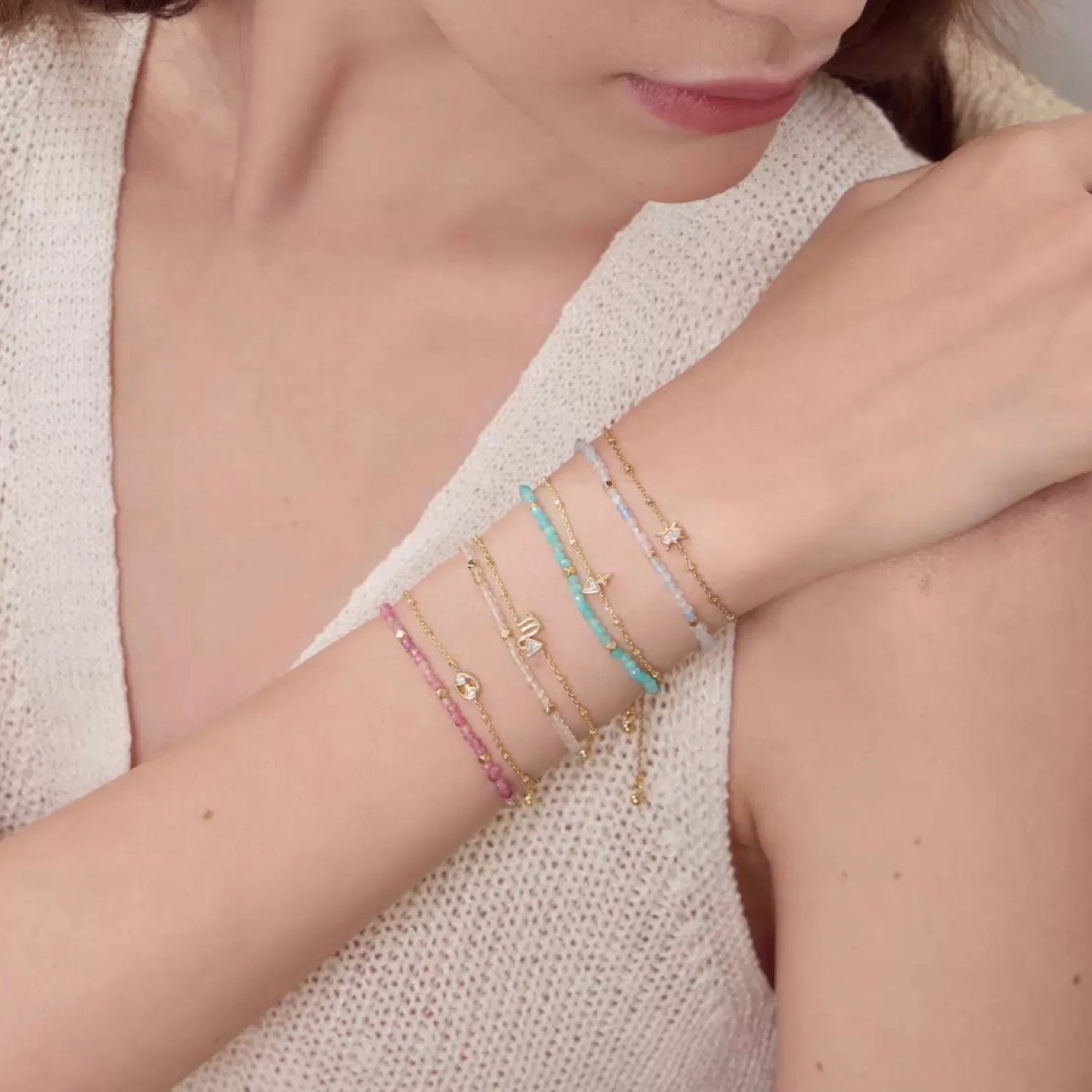 Close-up of a person's wrist wearing multiple bracelets on a neutral background for Constellation Gemini Zodiac Bracelet – Natural Crystal Adjustable | June Birthstone Jewelry Gift WJY studio